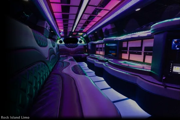 Interior view of a luxury party bus with purple and green LED lighting and plush seating.