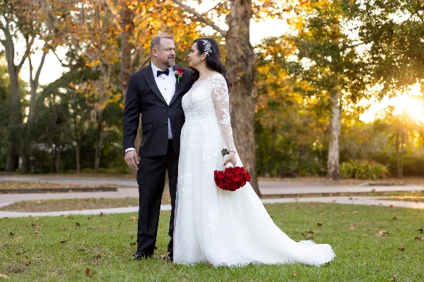 A bride and groom posing together in a garden setting during a wedding session.