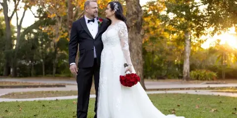 A bride and groom posing together in a garden setting during a wedding session.