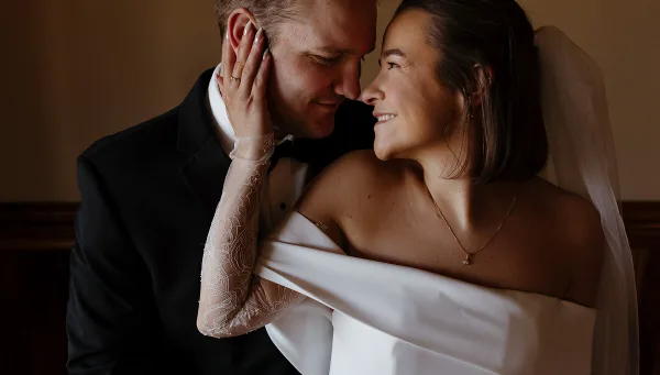 A bride and groom sharing an intimate moment, with the bride touching the groom's face.