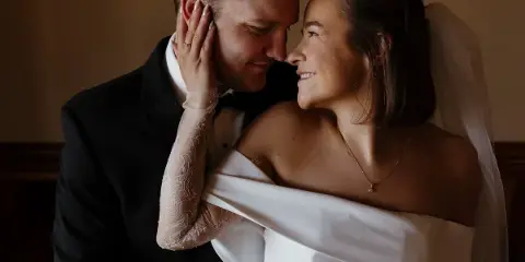 A bride and groom sharing an intimate moment, with the bride touching the groom's face.