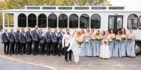 A wedding party posing outside of a Shooboo trolley