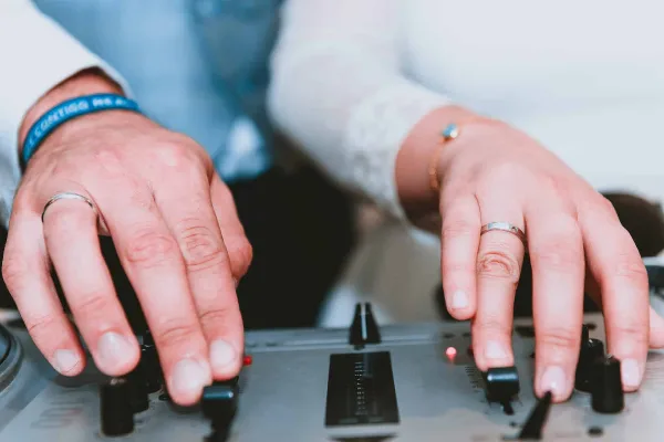 Close-up of hands adjusting knobs on a professional DJ mixer.