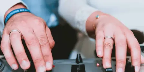 Close-up of hands adjusting knobs on a professional DJ mixer.
