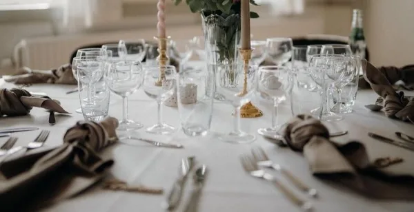 A close-up view of a formal event table setting featuring glassware, silverware, and fabric napkins.