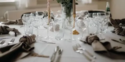 A close-up view of a formal event table setting featuring glassware, silverware, and fabric napkins.