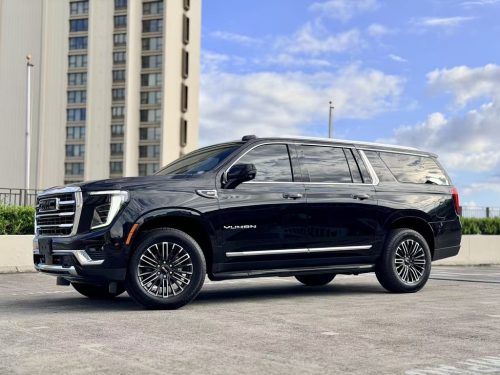 Black GMC Yukon SUV parked in front of a high-rise building