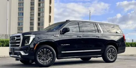 Black GMC Yukon SUV parked in front of a high-rise building