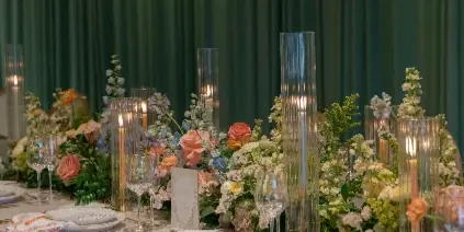 A close-up of an elegant wedding table setting with white linens, gold flatware, glassware, and floral centerpieces.