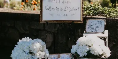 A wedding welcome sign for Emily and Michael decorated with a floral garland and flanked by buckets of white hydrangeas.