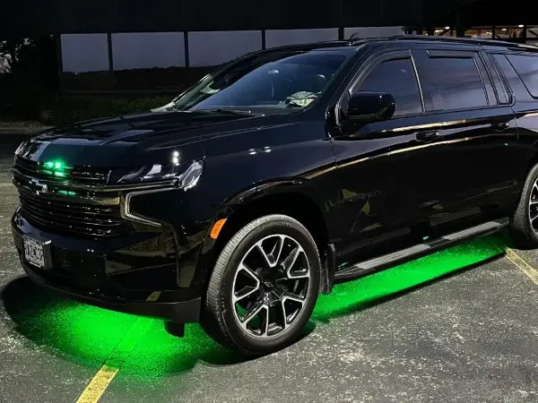A black Chevrolet SUV parked in a lot with green underglow lighting.
