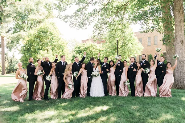 A wedding party posing outdoors on a lawn with the bride and groom in the center.