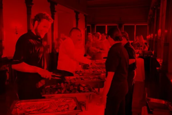 Catering staff serving food from trays to guests at an event.