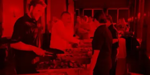 Catering staff serving food from trays to guests at an event.