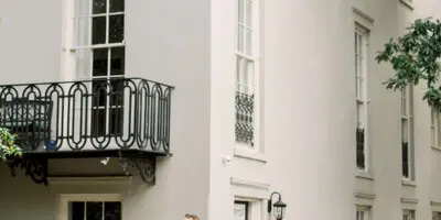 A bride and groom standing together on a sidewalk in front of a historic building with balconies.