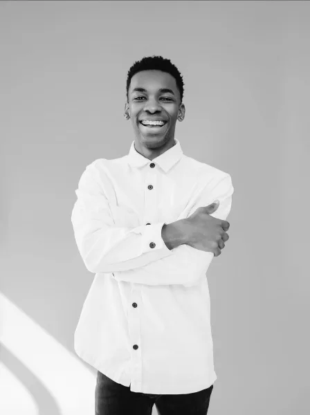 Black and white portrait of a smiling man in a white button-down shirt with arms crossed.