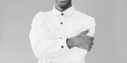 Black and white portrait of a smiling man in a white button-down shirt with arms crossed.