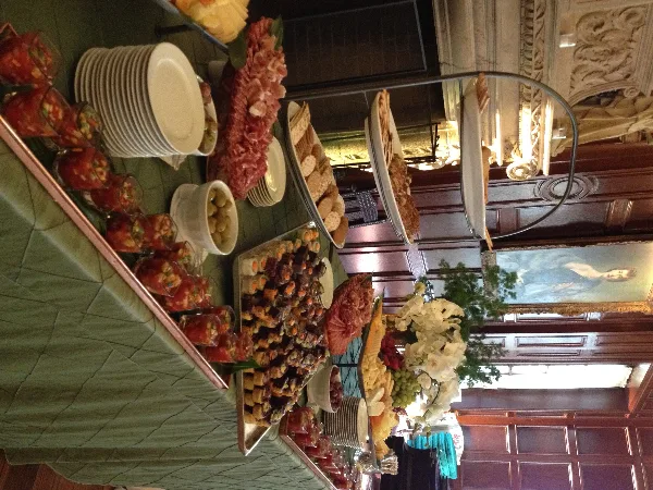 A catering buffet table set with various appetizers, charcuterie, and plates in an event venue.