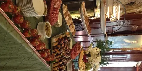 A catering buffet table set with various appetizers, charcuterie, and plates in an event venue.