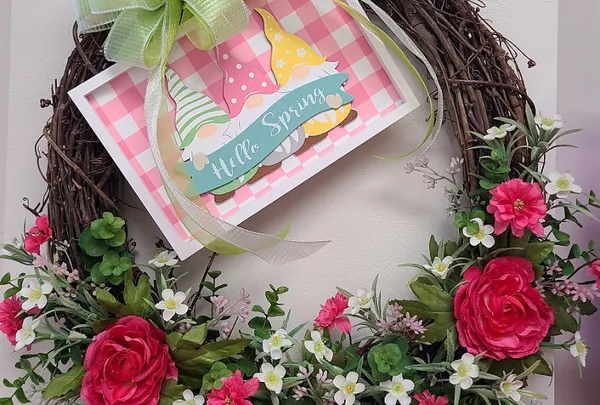 A floral wreath with pink roses and greenery featuring a 'Hello Spring' card.
