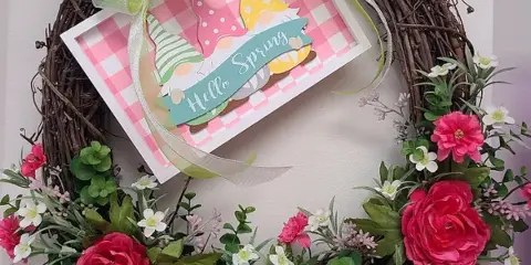 A floral wreath with pink roses and greenery featuring a 'Hello Spring' card.