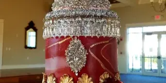Ornate multi-tier pink and burgundy wedding cake decorated with gold and crystal details.