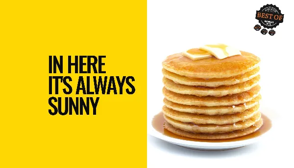 A tall stack of pancakes topped with butter and syrup on a white plate.