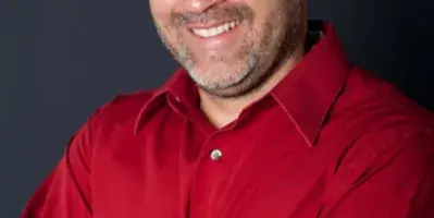 Portrait of Robert Cobo, owner of Siskiyou DJ, wearing a red shirt.
