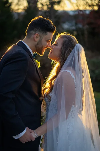 A bride and groom holding hands and smiling at each other during a golden hour wedding portrait.