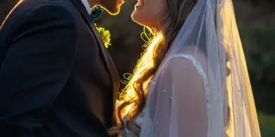A bride and groom holding hands and smiling at each other during a golden hour wedding portrait.