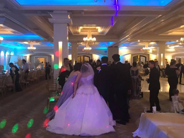Bride and groom dancing at a wedding reception with colorful ambient lighting.