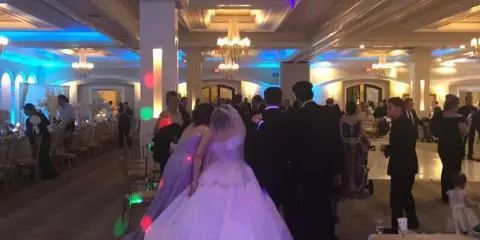 Bride and groom dancing at a wedding reception with colorful ambient lighting.