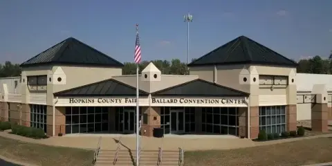 Exterior view of the Ballard Convention Center building with signage and an American flag.