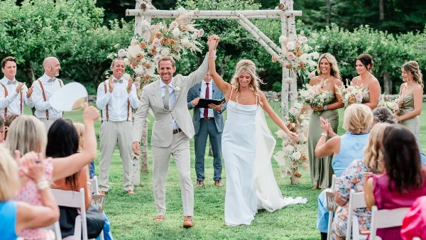 A bride and groom walking down the aisle after their wedding ceremony, holding hands and smiling.