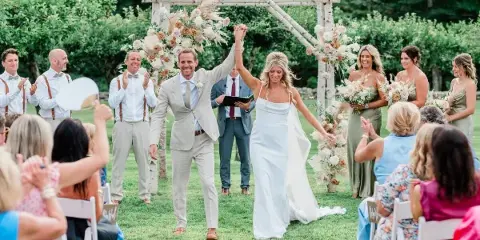 A bride and groom walking down the aisle after their wedding ceremony, holding hands and smiling.