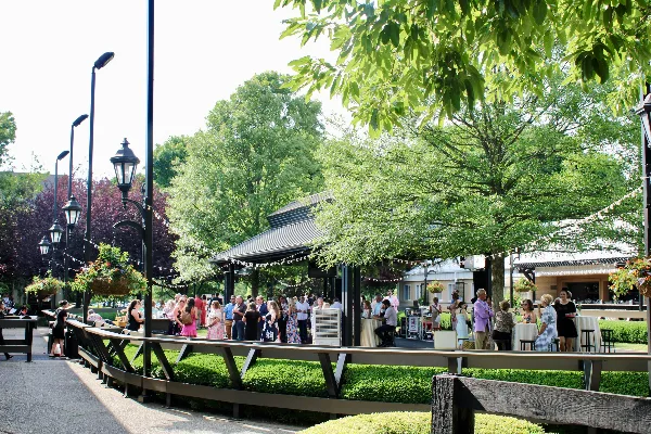 Outdoor event venue with a crowd of guests gathered around a pavilion and string lights.