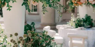 Elegant wedding table setting with lush floral centerpieces, greenery, glassware, and place settings in a classical venue.