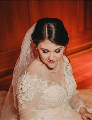A bride in a white lace wedding dress and veil with a professional updo hairstyle.