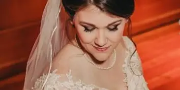 A bride in a white lace wedding dress and veil with a professional updo hairstyle.
