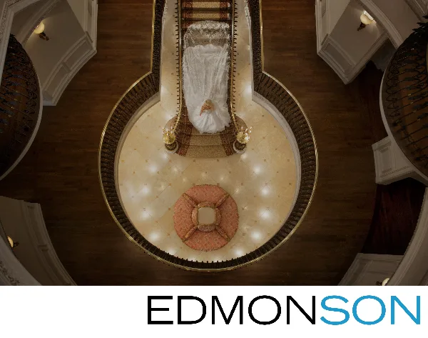Overhead view of a bride in a white wedding dress standing in a grand, circular architectural atrium with ornate railings and wood flooring.