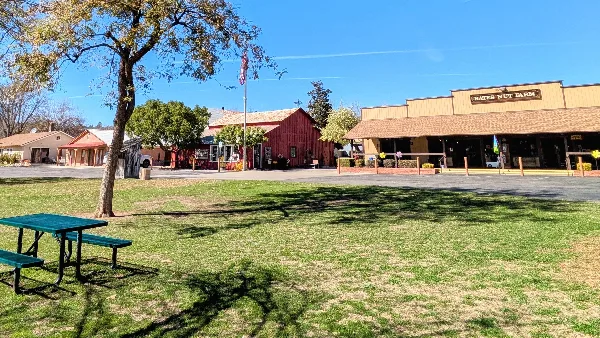 Exterior view of the Bates Nut Farm venue featuring a red barn, main building with signage, mature trees, and a grassy lawn area.