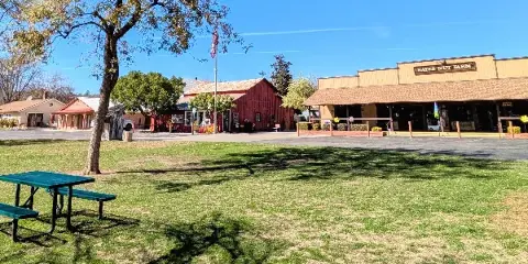 Exterior view of the Bates Nut Farm venue featuring a red barn, main building with signage, mature trees, and a grassy lawn area.