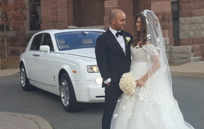A bride and groom standing next to a white Rolls-Royce limousine.