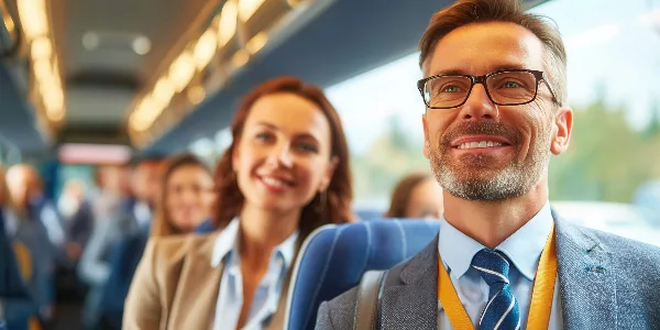 Passengers seated inside a bus, with a man in the foreground smiling.