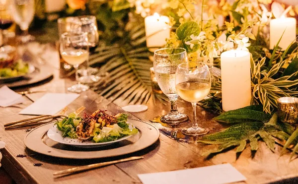 A plated salad dish served on a table with wine glasses and floral arrangements.