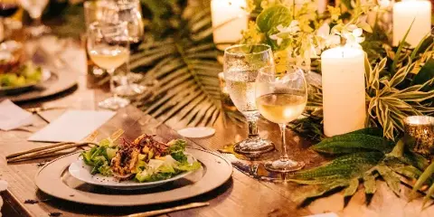 A plated salad dish served on a table with wine glasses and floral arrangements.