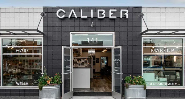 Exterior view of the Caliber Hair & Makeup Studio storefront with open doors and product displays in the windows.