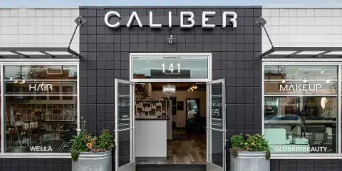 Exterior view of the Caliber Hair & Makeup Studio storefront with open doors and product displays in the windows.
