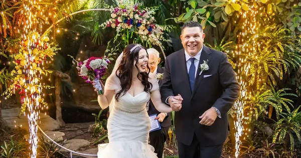 A bride and groom laughing joyfully as they walk through a sparkler exit at a wedding reception.