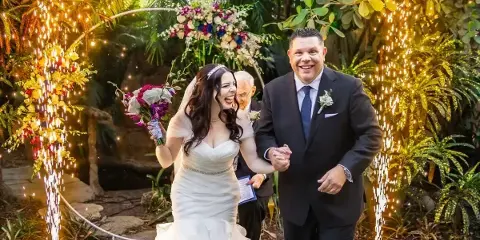A bride and groom laughing joyfully as they walk through a sparkler exit at a wedding reception.